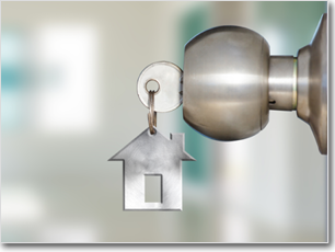 Doorknob with a key inserted. The key is connected to a house-shaped key fob.