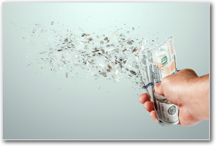 Hand holding money dollar bills that are disappearing.