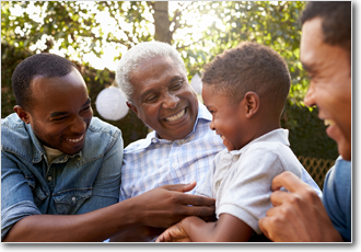 A grandfather, sons, and grandson smile together in a garden.
